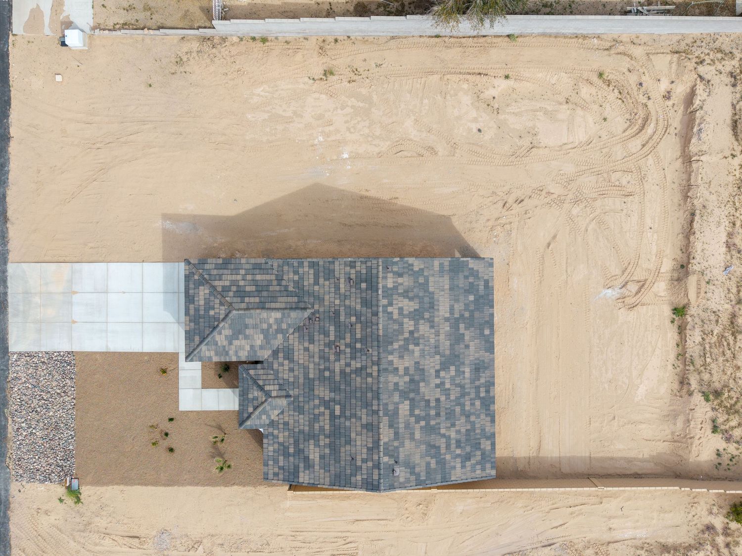 A long aerial view of solar panels installed on a sandy desert terrain with scattered vegetation.