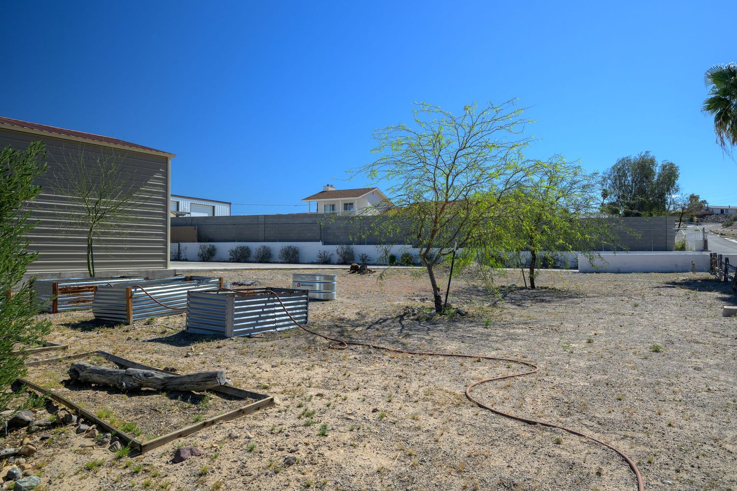 Panoramic desert landscape with scattered buildings and sparse vegetation under bright blue sky.
