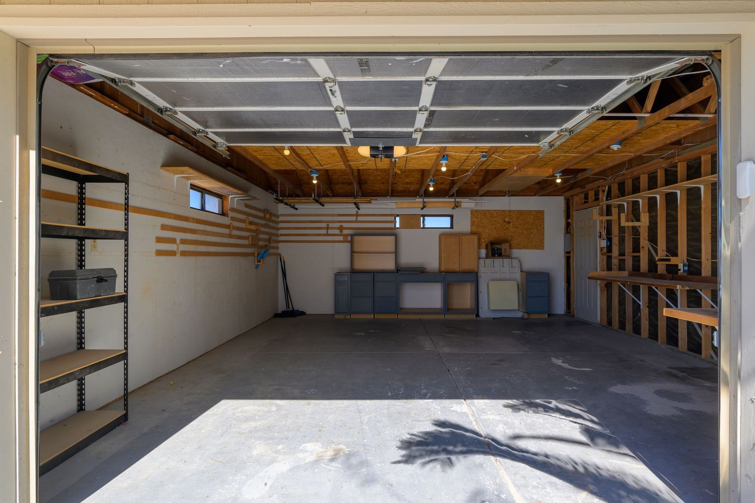 Interior view of an empty storage unit facility with white walls, concrete floors, and overhead lighting.