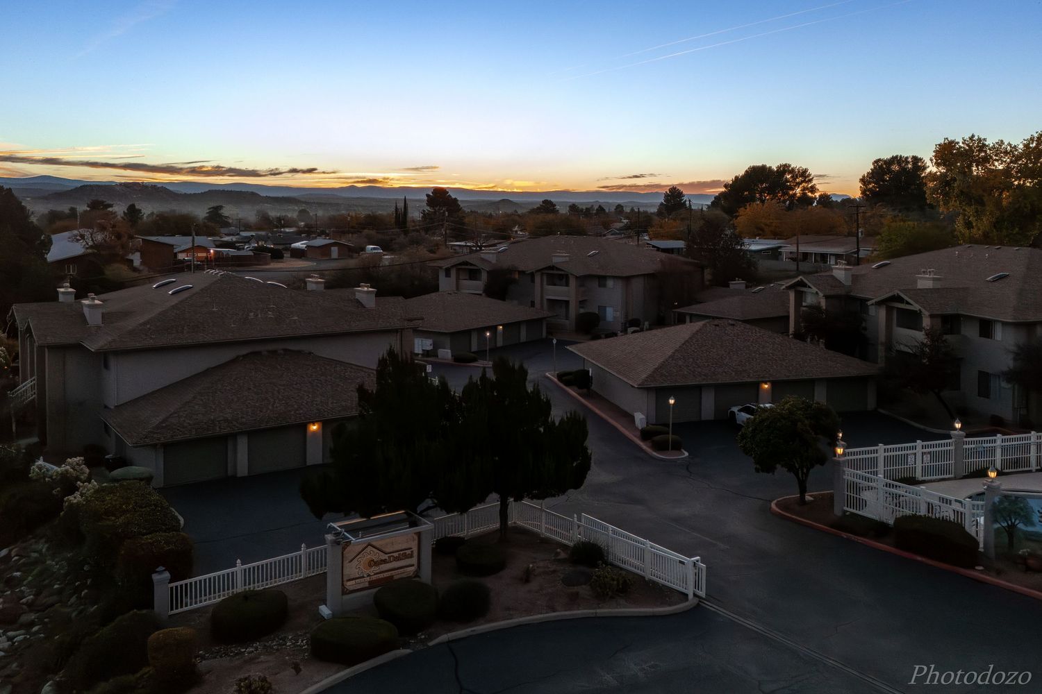 A panoramic view of residential homes and rooftops in a suburban neighborhood at dusk with a blue sky overhead.
