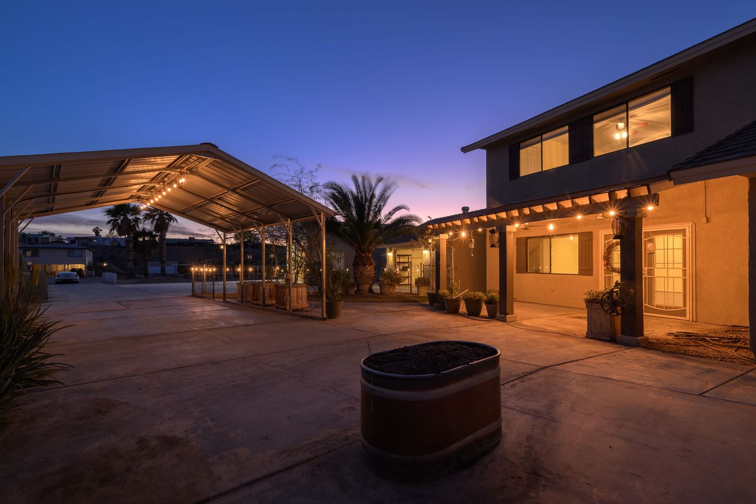 Desert home exterior illuminated at dusk with warm lighting and modern architectural features against a purple sky.