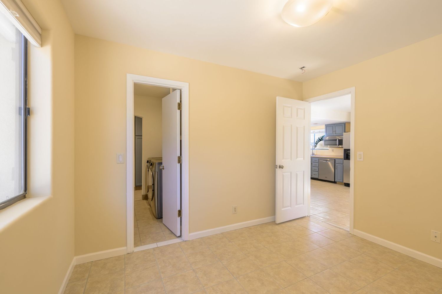 Interior hallway with beige walls and white trim showing multiple doorways and natural lighting from windows.