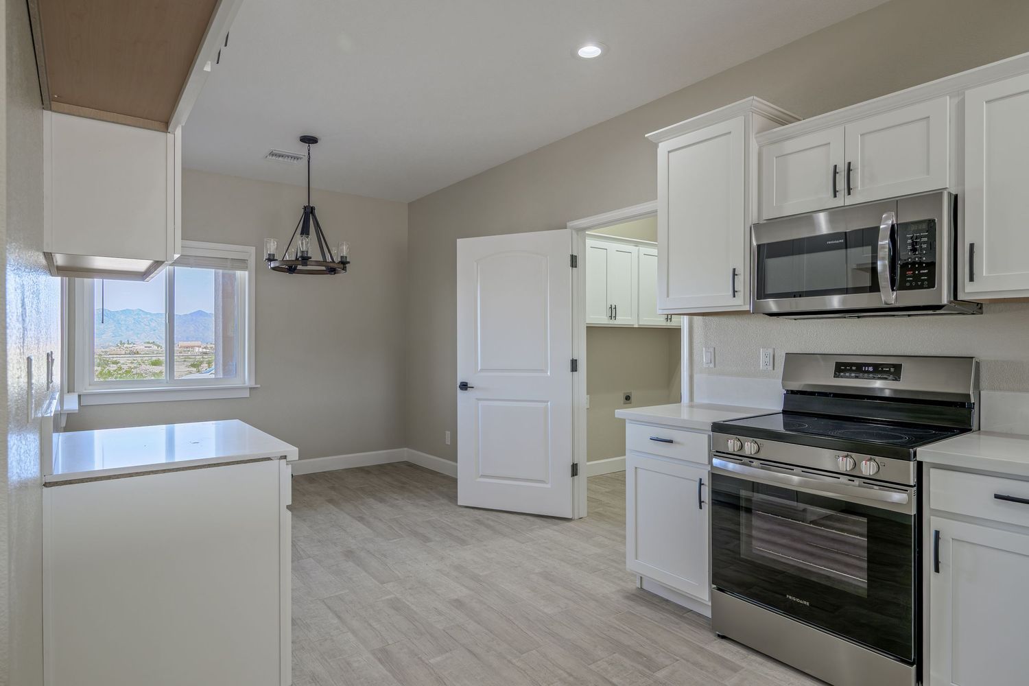 Modern kitchen interior with white cabinets, black appliances, and pendant lighting showcases clean lines and open layout design.