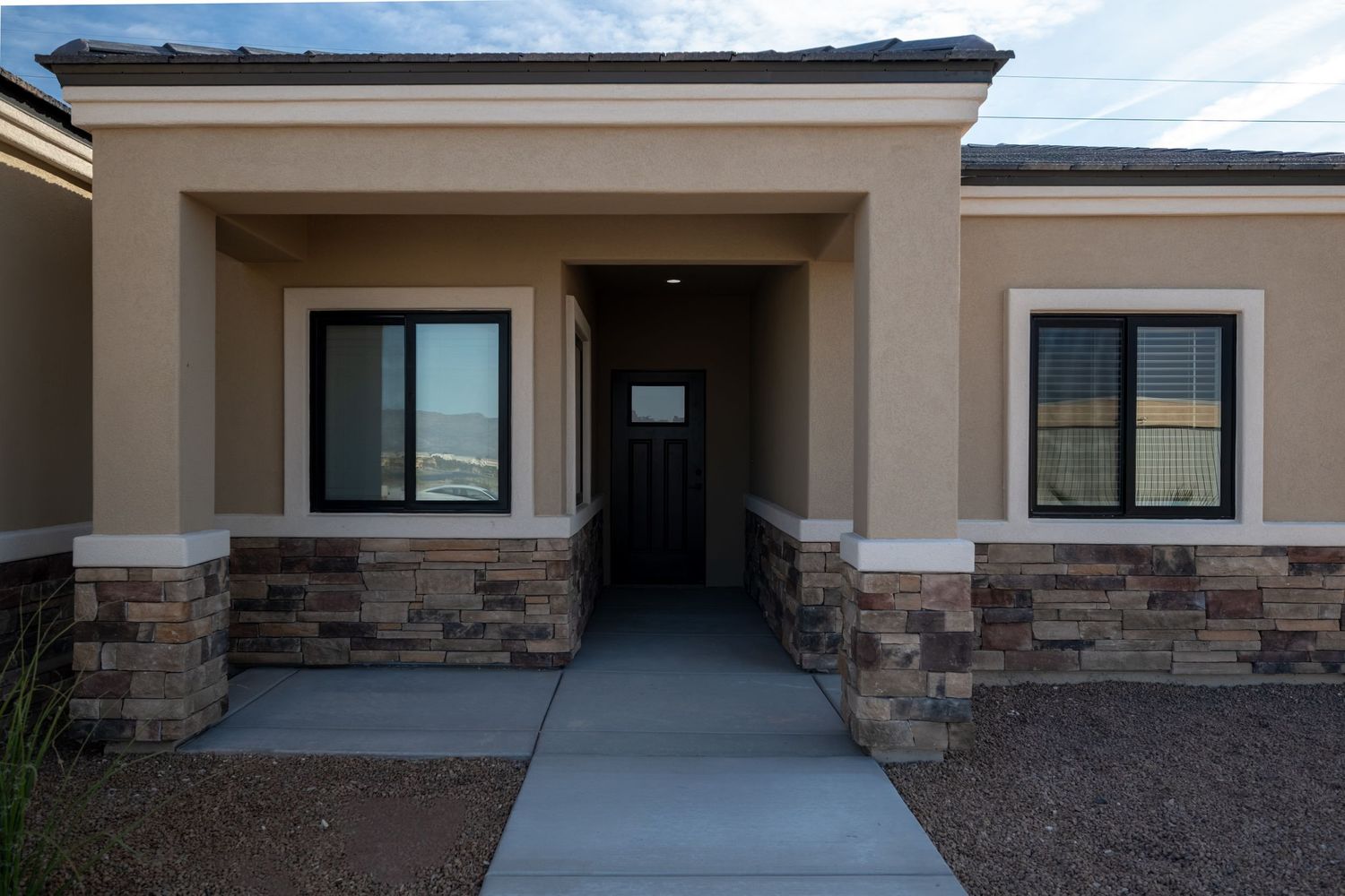 Modern commercial building exterior with stone facade and large windows in a beige color scheme.