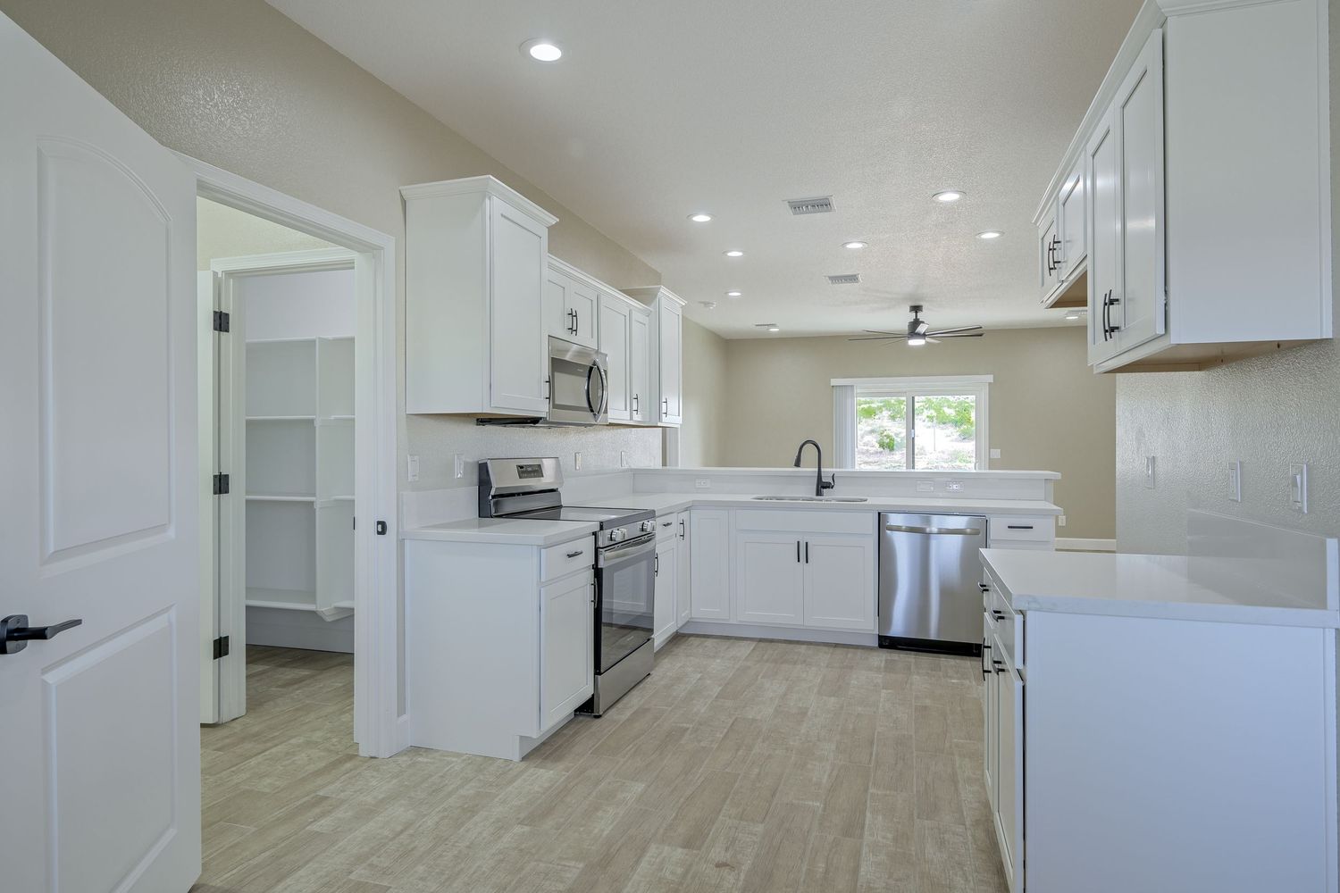 Open concept living space with white kitchen cabinets, modern appliances, and neutral flooring throughout.