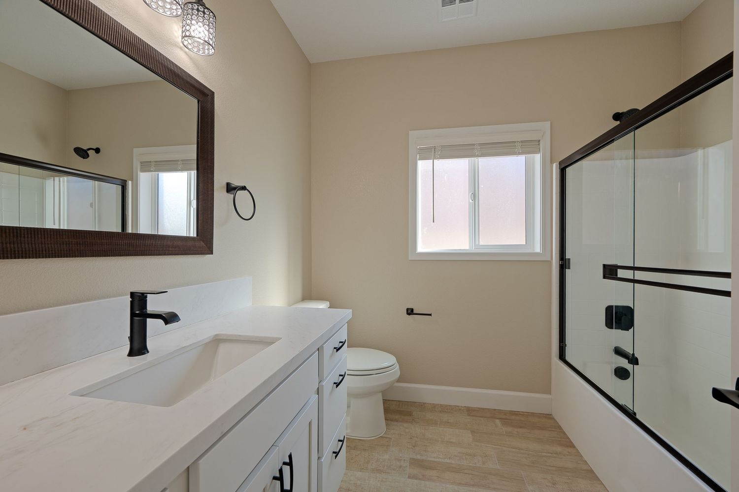 Modern bathroom interior with glass shower enclosure, beige walls, and dark wood accents.