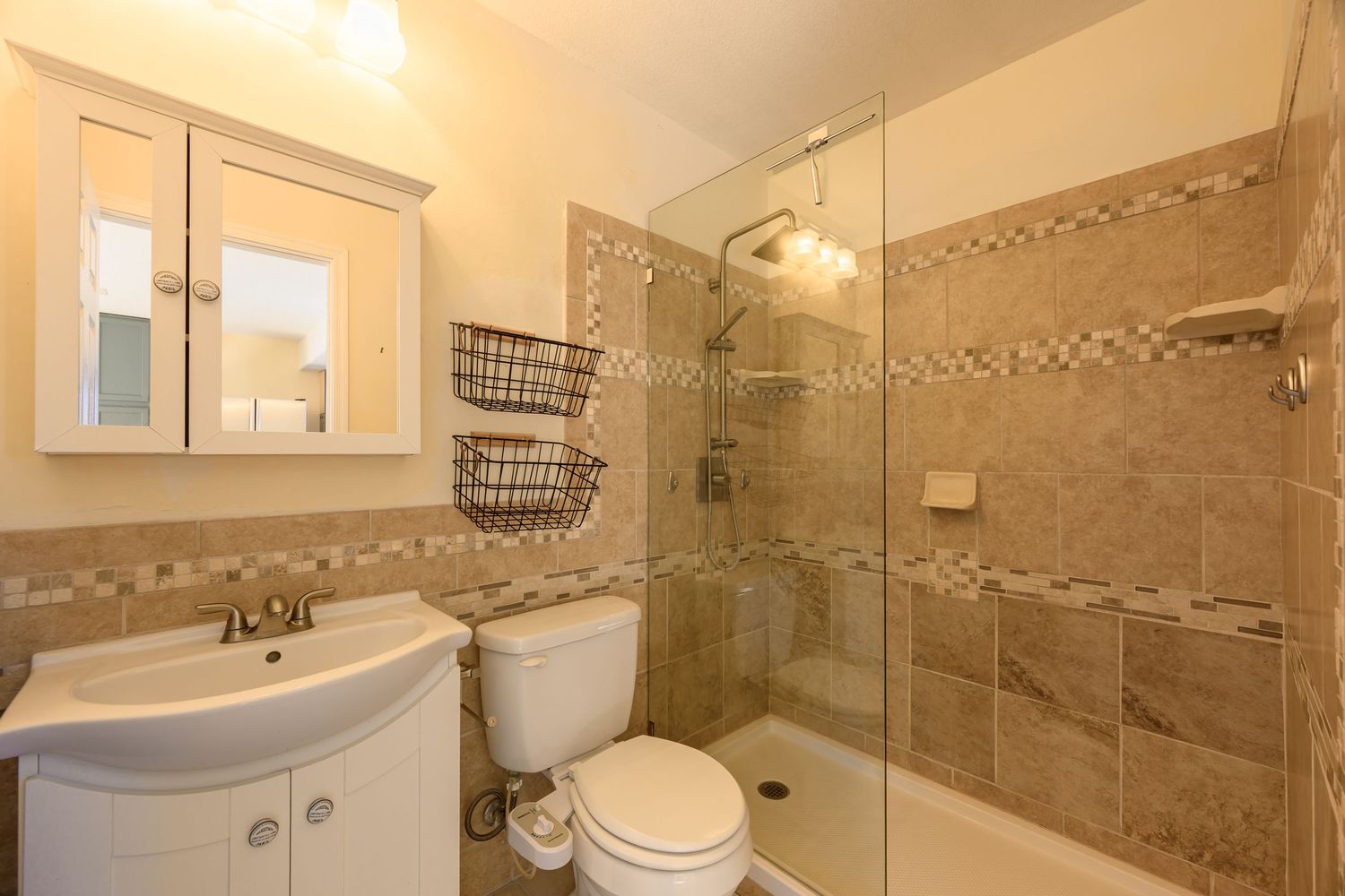 Modern bathroom interior with beige tile walls, white cabinets, and glass shower enclosure showcasing elegant design elements.