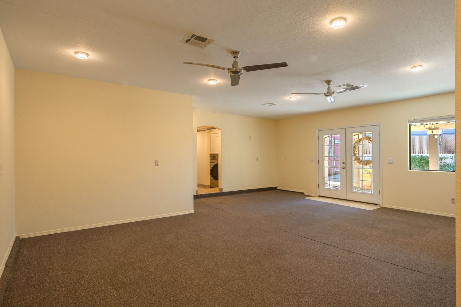 Large empty room with beige walls, recessed lighting, and ceiling fan showing different angles of the interior space.