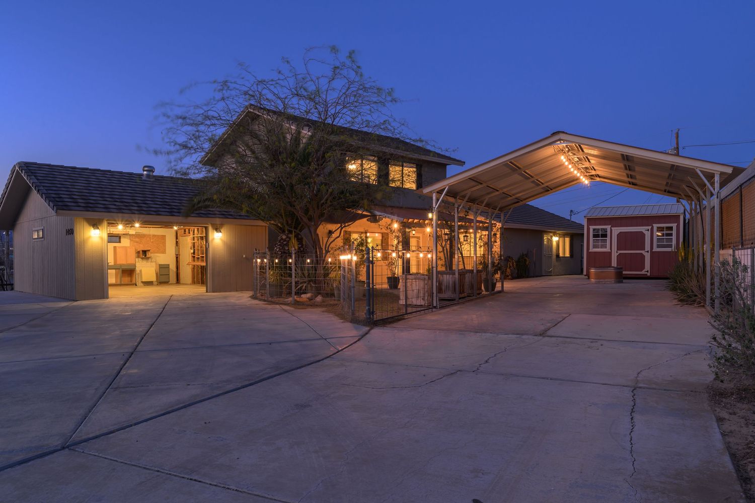 Exterior view of illuminated modern buildings at dusk with warm lighting glowing from windows and walkways.