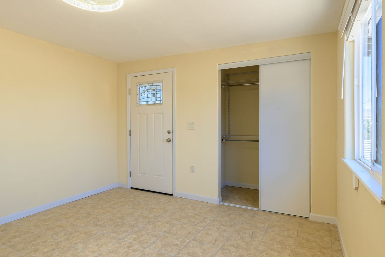 Empty beige room with light carpet flooring, white trim, and recessed lighting in a residential setting.