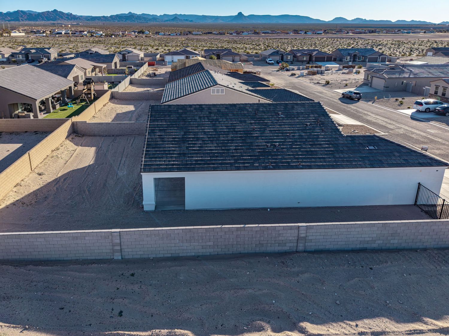 Panoramic view of desert homes with mountains in the distance and clear blue skies above.