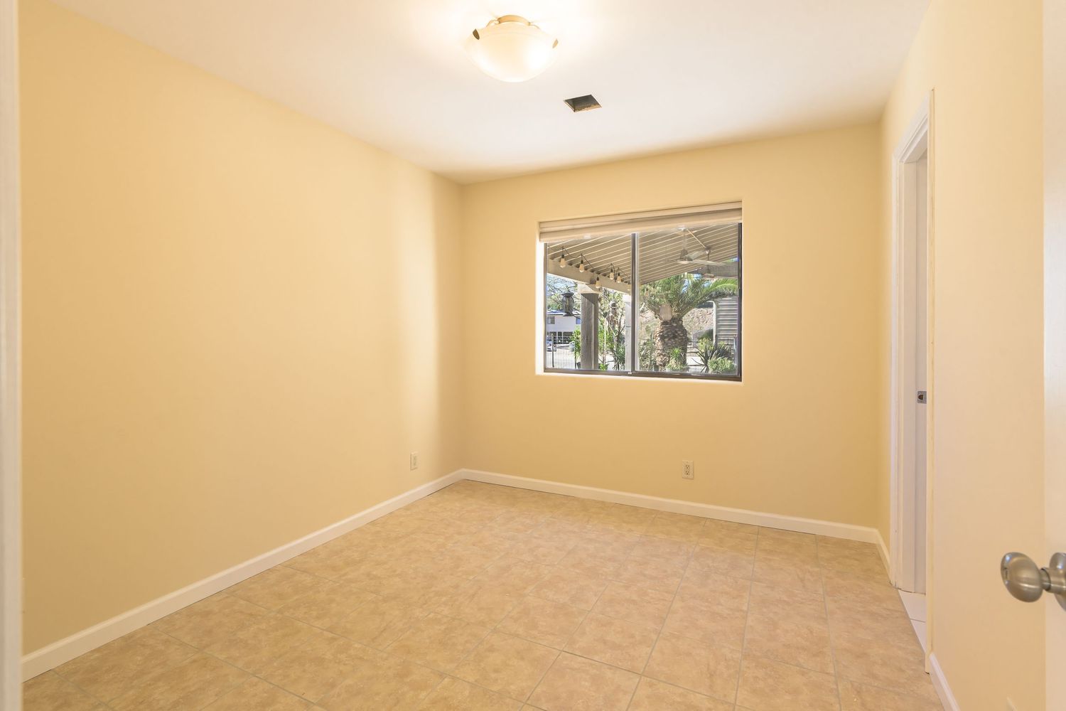 A bright, empty room with beige walls, recessed lighting, and a framed artwork hanging on the wall.