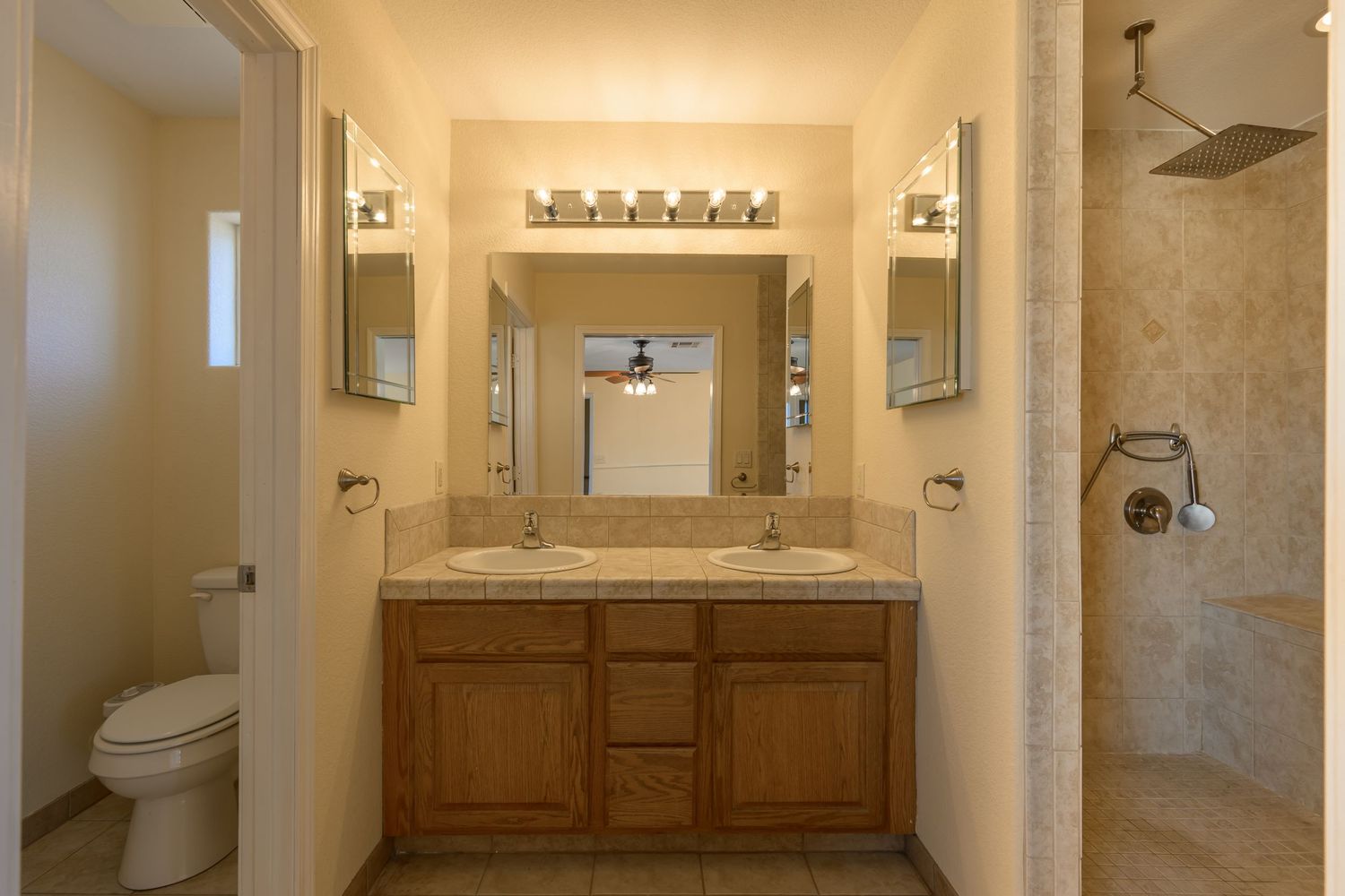 Spacious master bathroom with dual sinks, wooden cabinetry, decorative sconces, and walk-in shower.