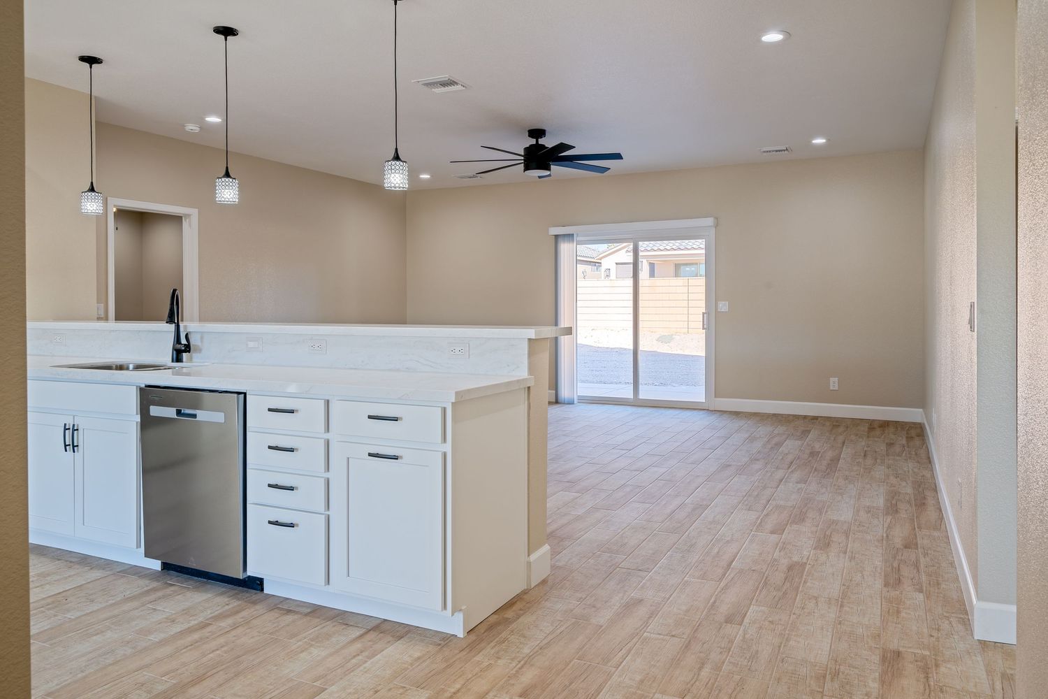 Modern open concept living area with light hardwood floors, white cabinets, and recessed lighting throughout.
