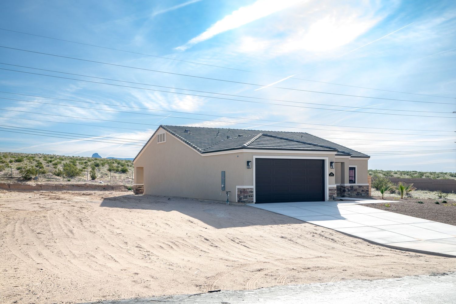 A series of exterior home construction photos showing different stages of building progress in a desert landscape setting.