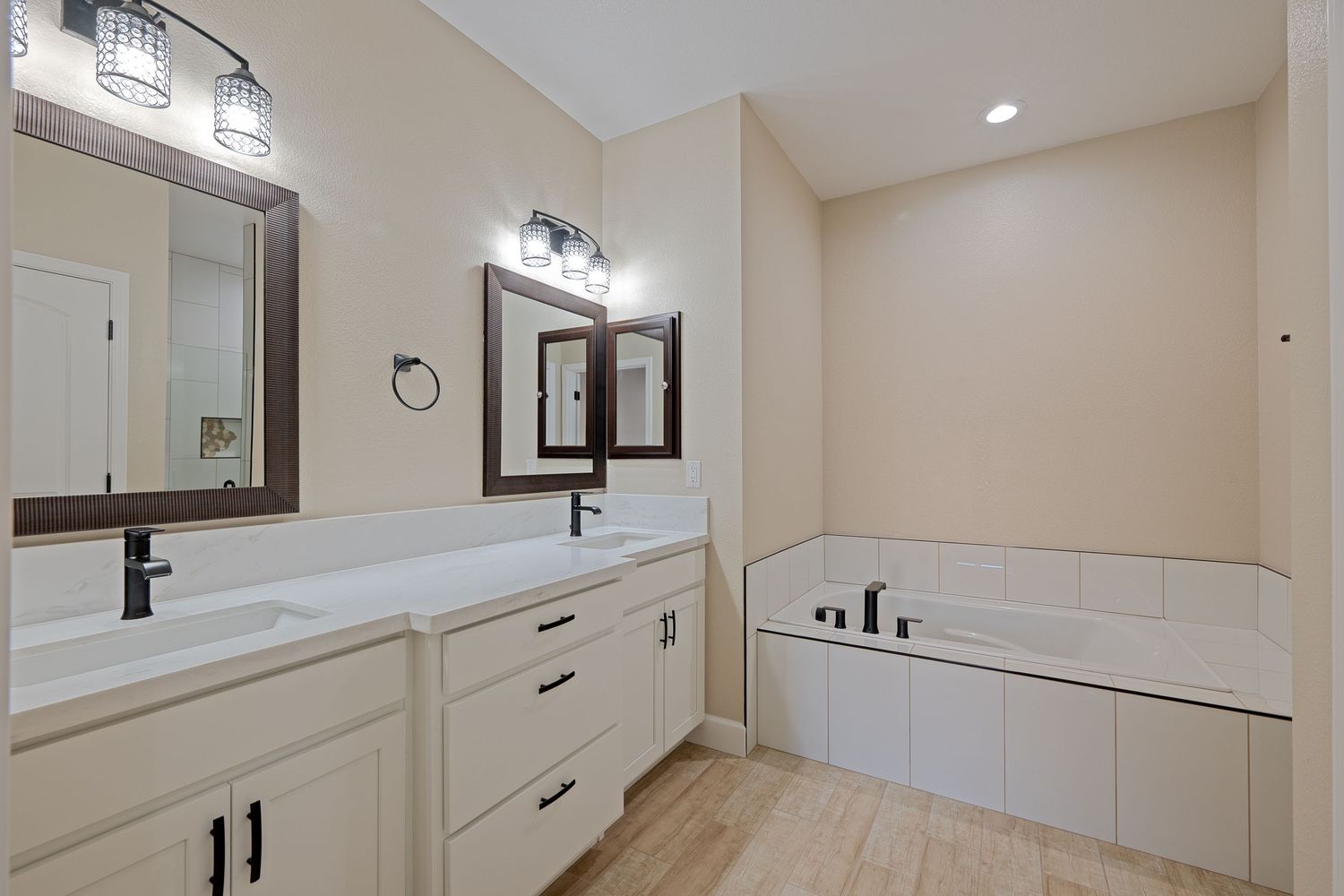 Modern white bathroom with double vanity, large mirror, and recessed lighting showcases clean lines and neutral decor.