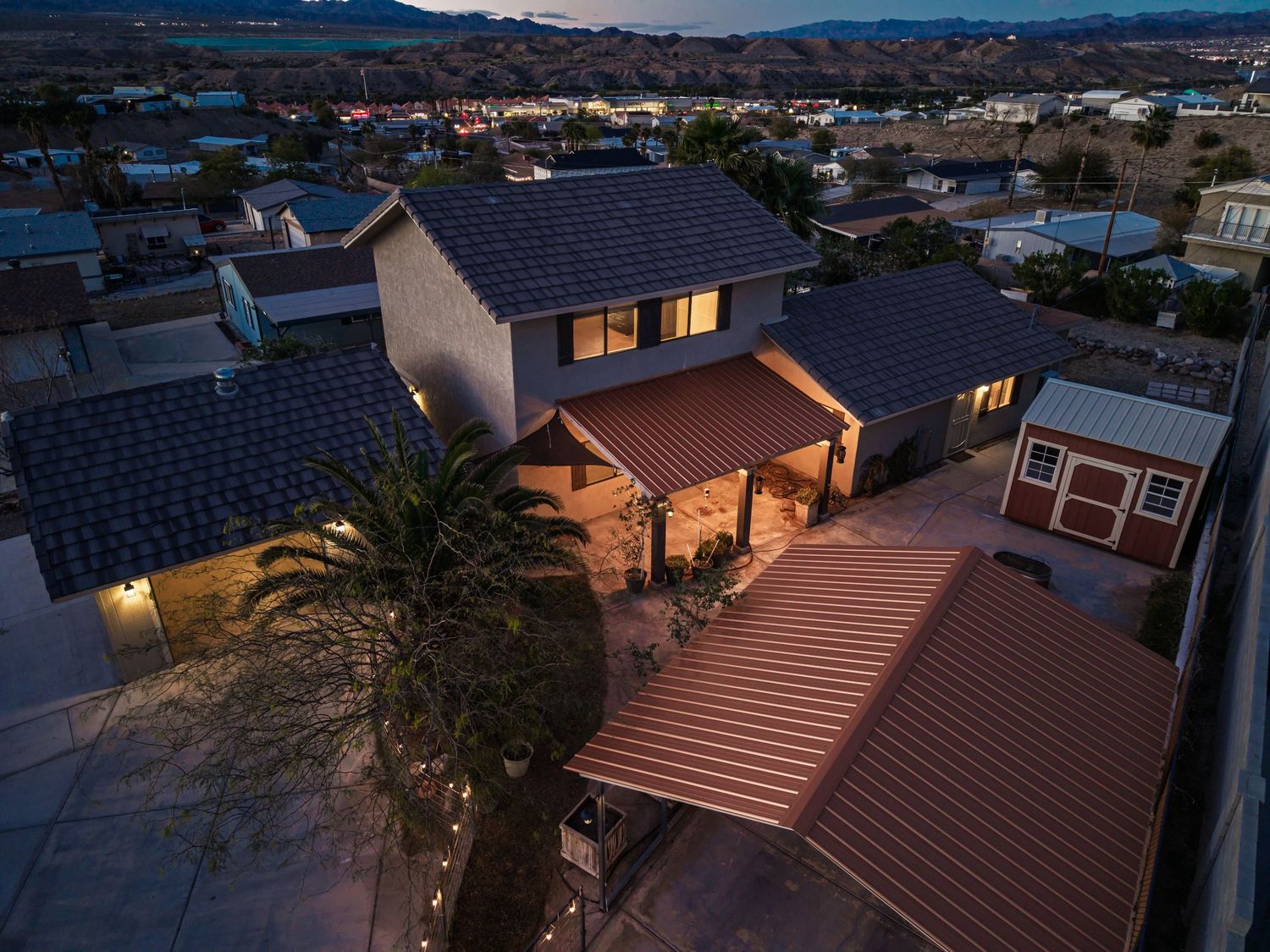 Aerial twilight view of modern suburban home with solar panels and terracotta roof in residential neighborhood.