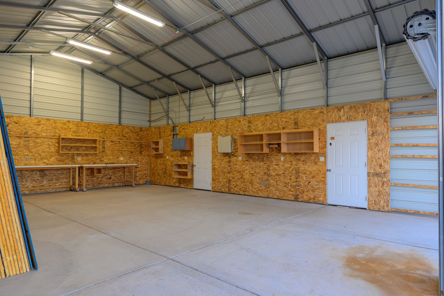 Large empty warehouse interior with metal ceiling, concrete floor, and wooden wall panels showing multiple storage bays.