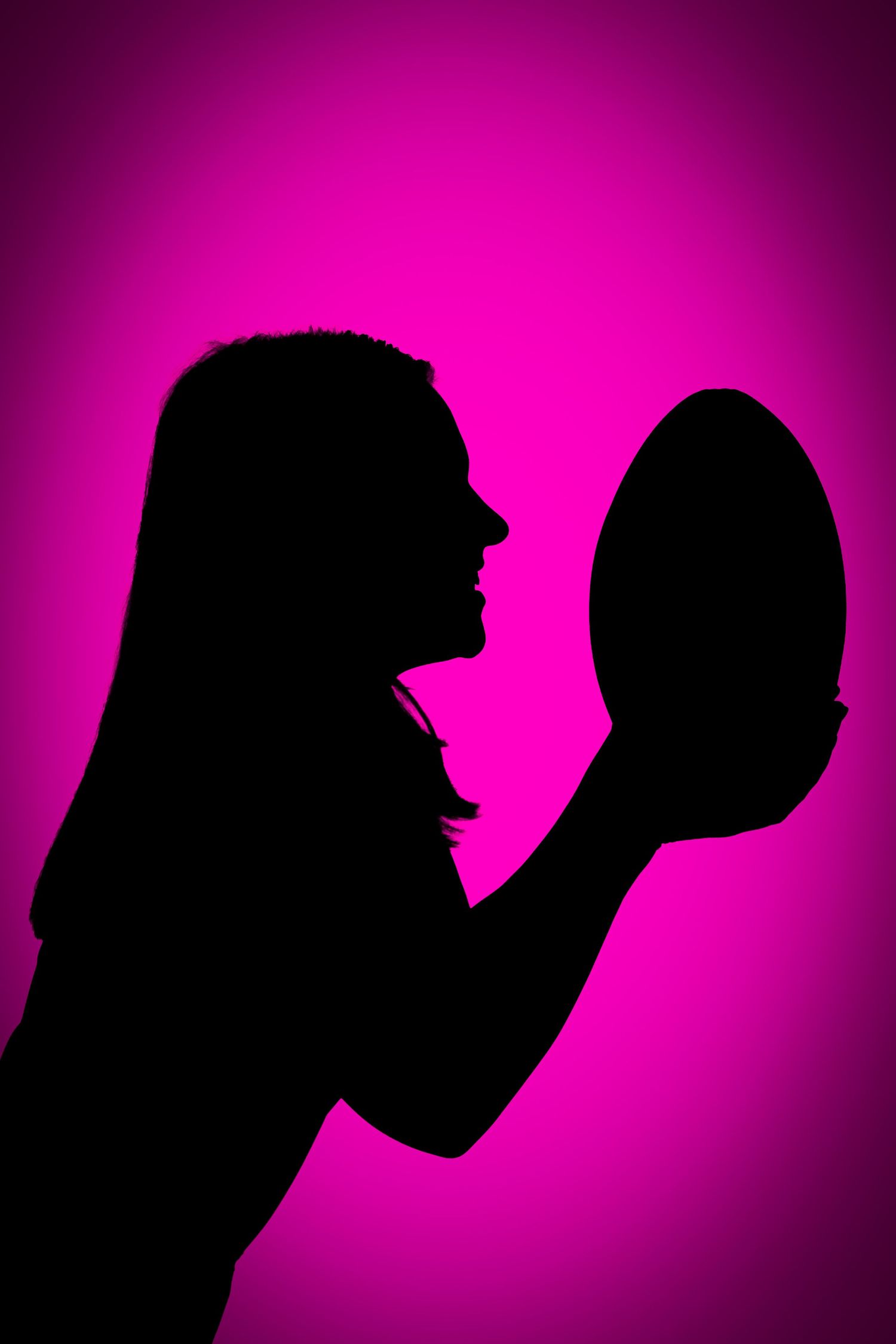 Side-profile silhouette of a person holding a rugby ball up to their face against a bright magenta pink background.