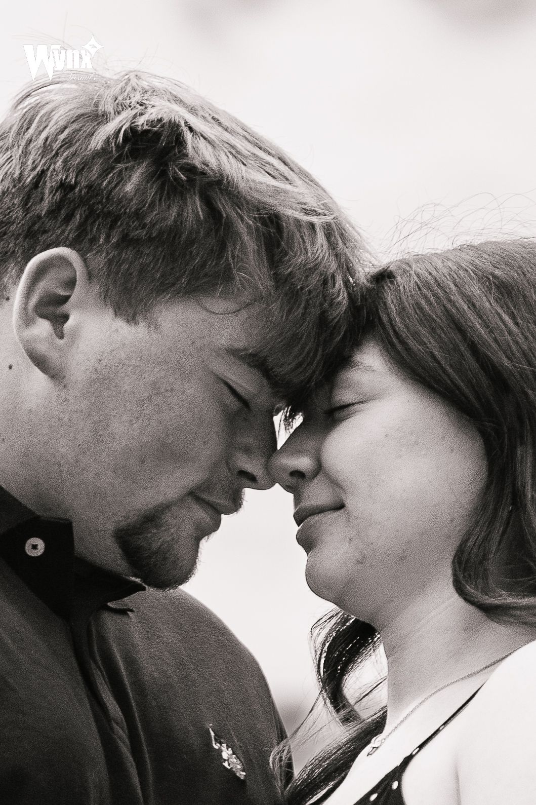 Black and white close-up of a couple touching foreheads with eyes closed in a tender, romantic engagement portrait.