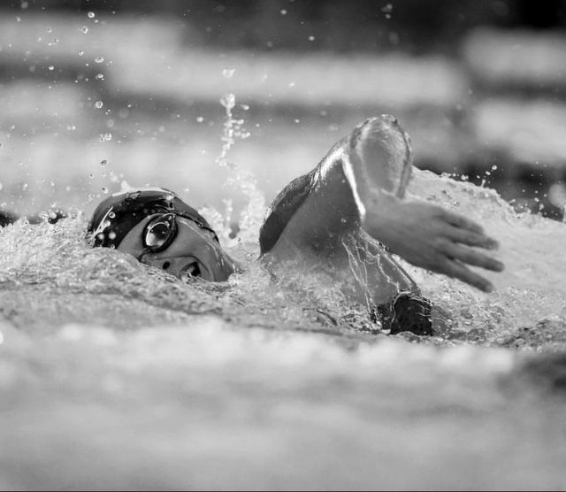 Close-up sequence of competitive swimming strokes in black and white.