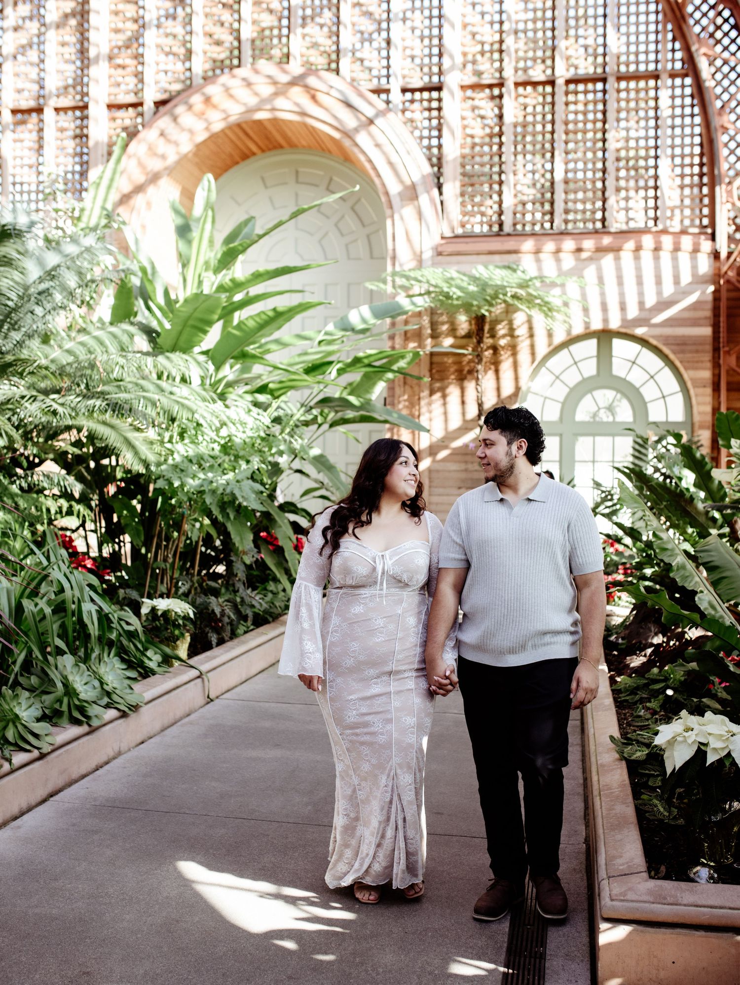 Balboa Park Engagement Portrait Photographer; romantic couple walking, holding hands, gazing at each other in a greenhouse