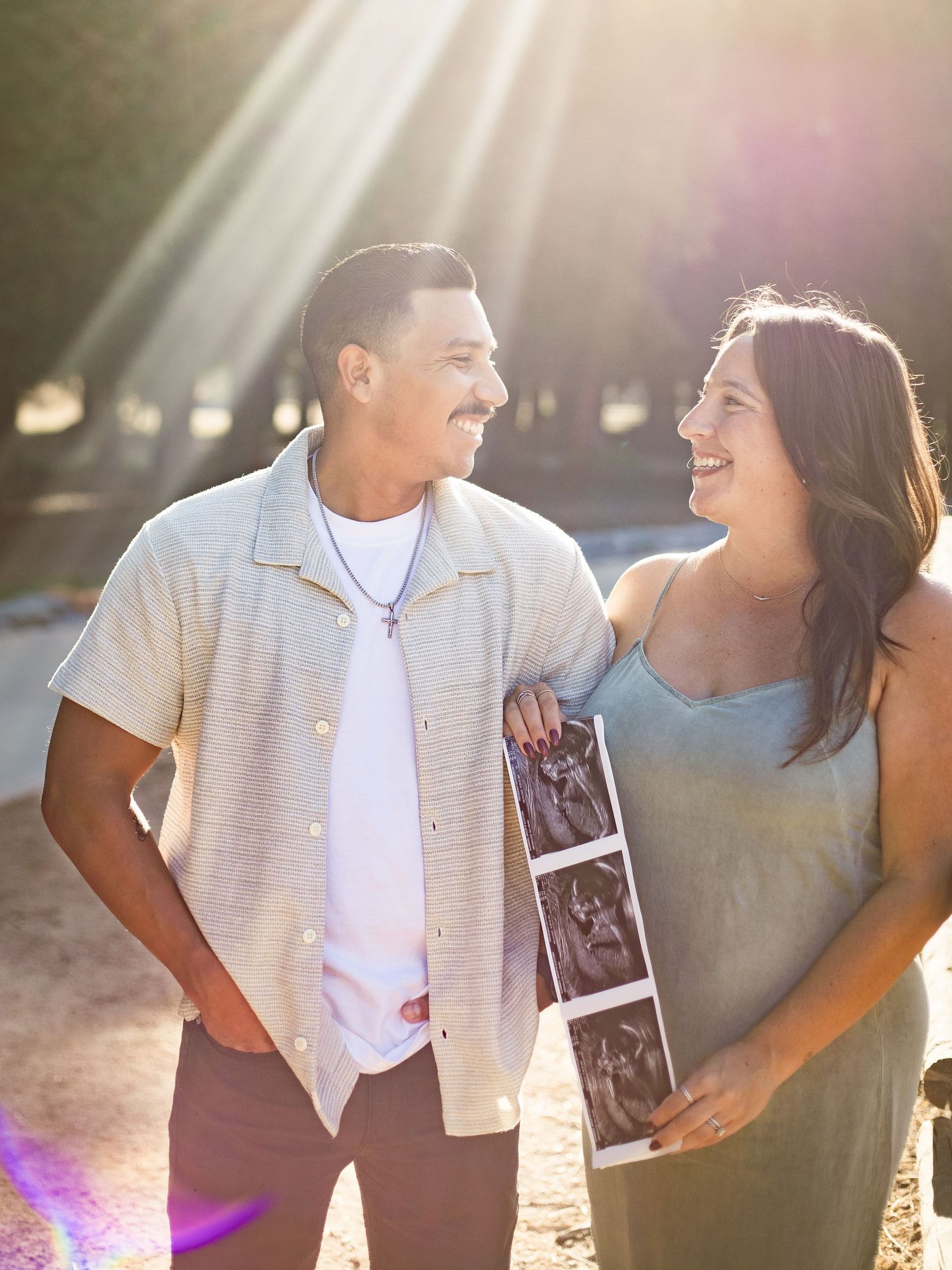 Maternity session at Carbon Canyon Regional Park where couple is standing and smiling while holding the strip of ultrasound images.