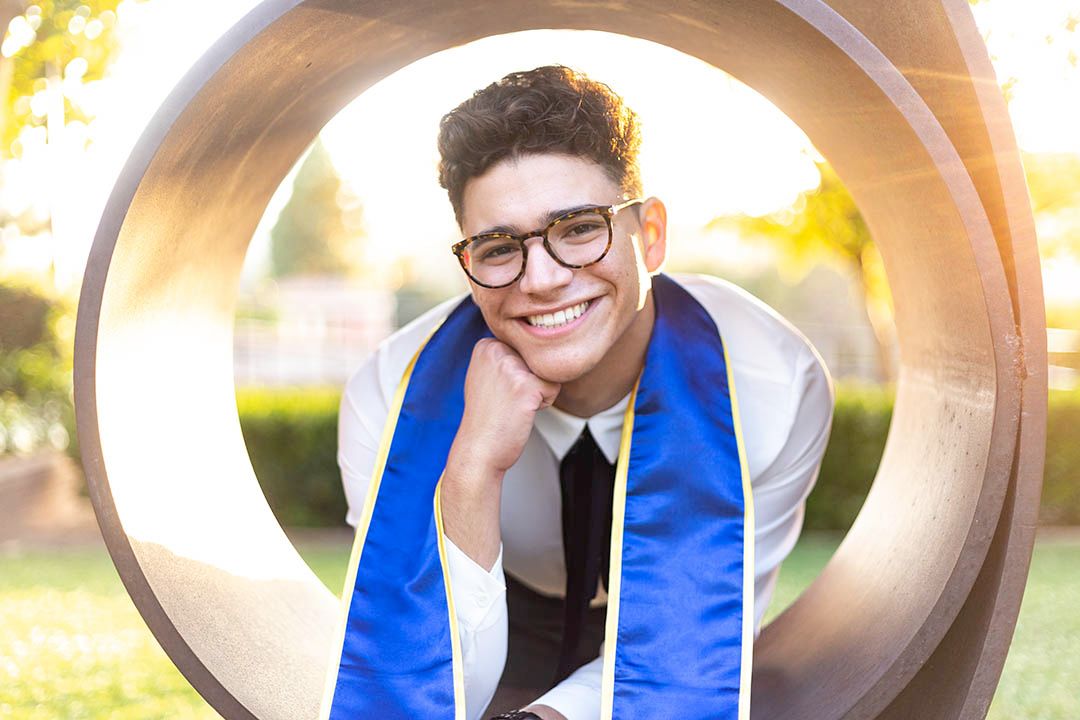 UCLA graduate portrait of a smiling male graduate framed inside the “L'Occhio del Cielo” sculpture behind Royce Hall at UCLA