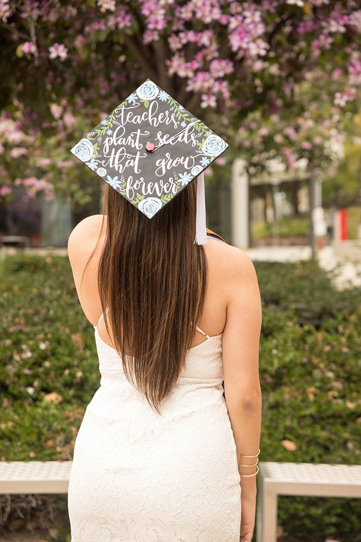 CSUF graduate in a white dress with long hair, standing with her back to the camera so she can show off her decorated graduation cap
