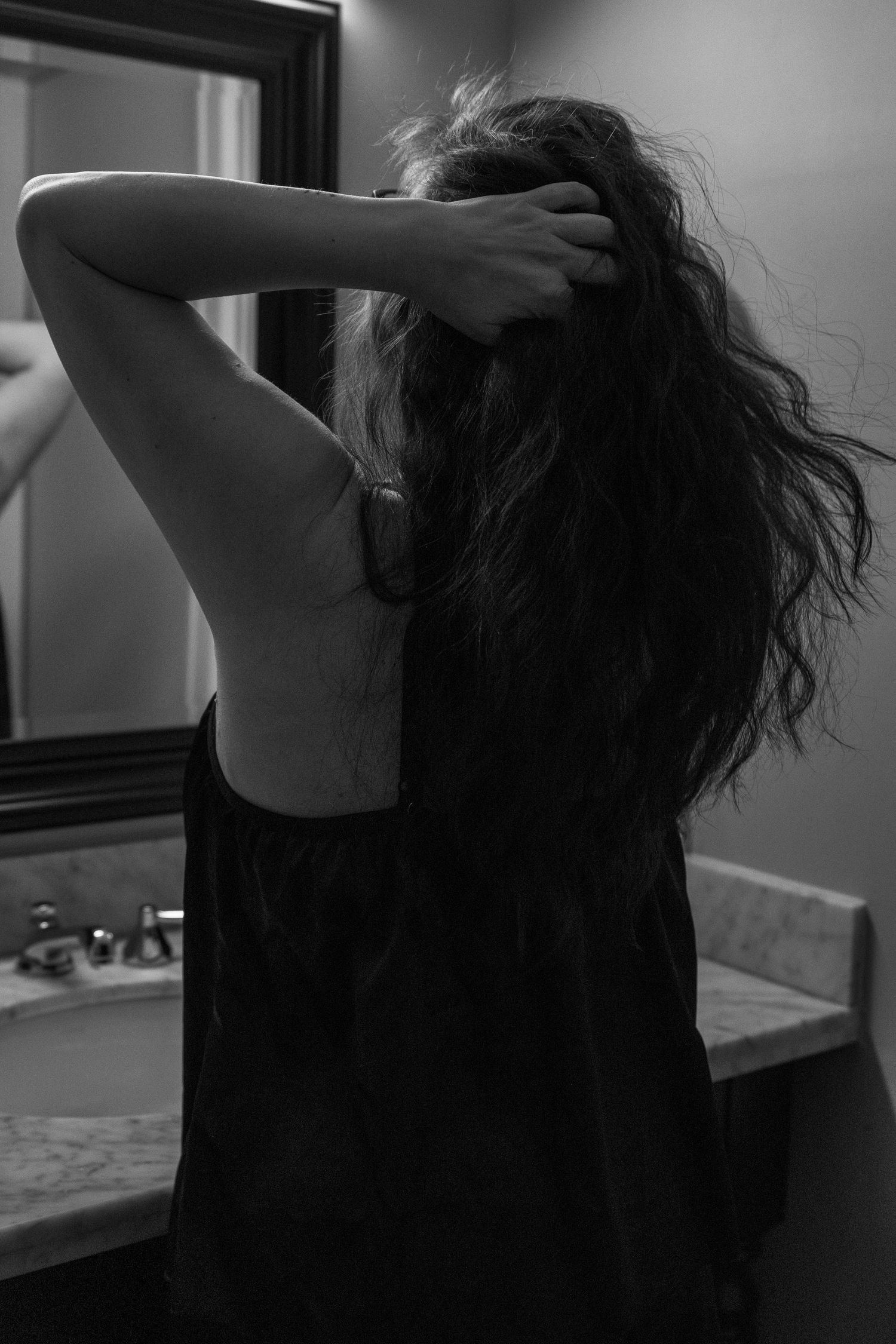 Black and white portrait showing someone running fingers through long dark hair.
