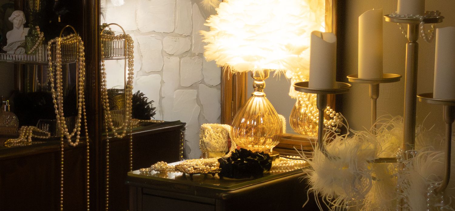 Warm glowing chandeliers and ornate wall sconces illuminate an elegant ballroom with classic architectural details.