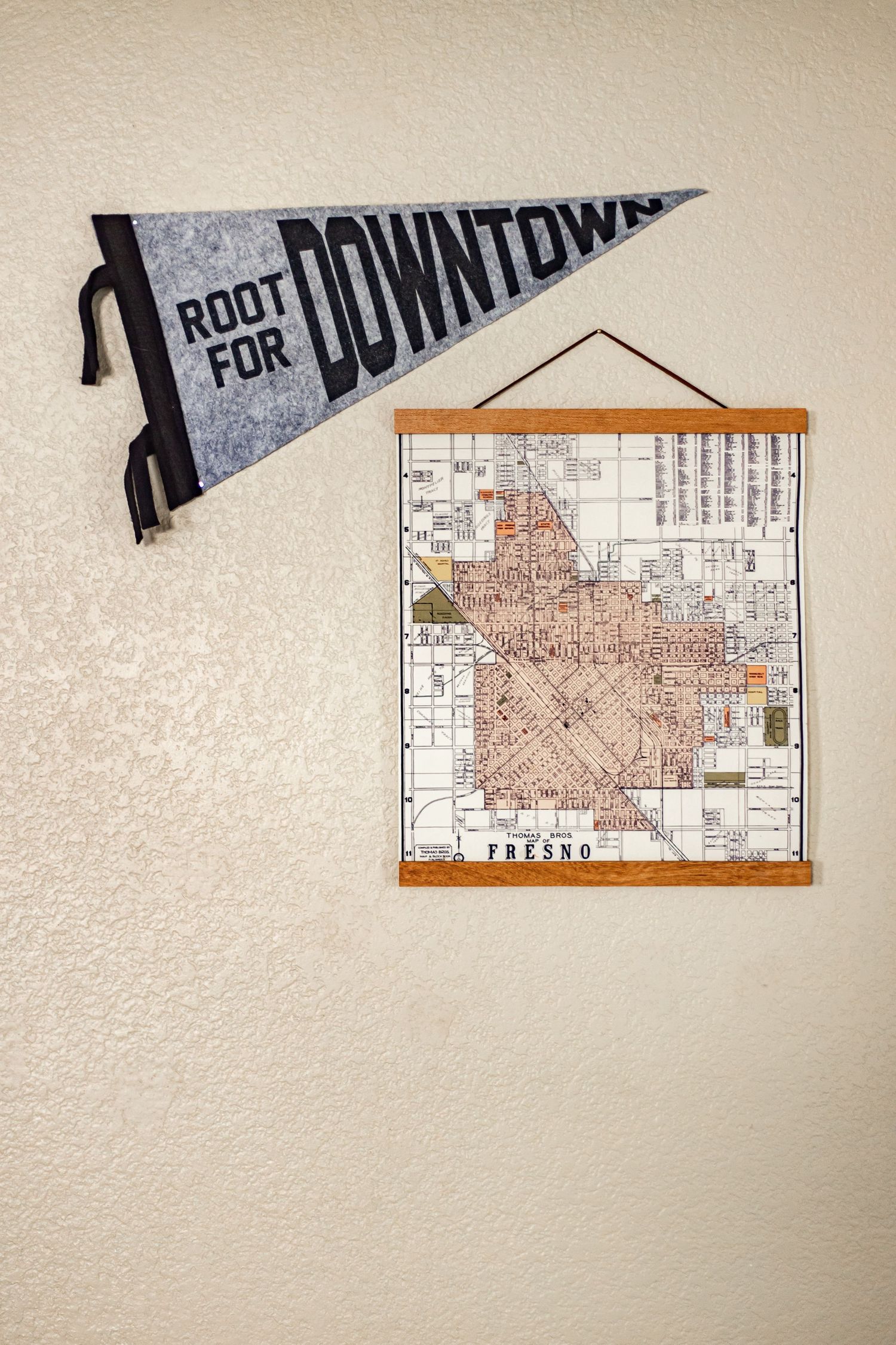 A series of vintage-style maps and pennants displayed on a beige wall create a minimalist gallery arrangement.