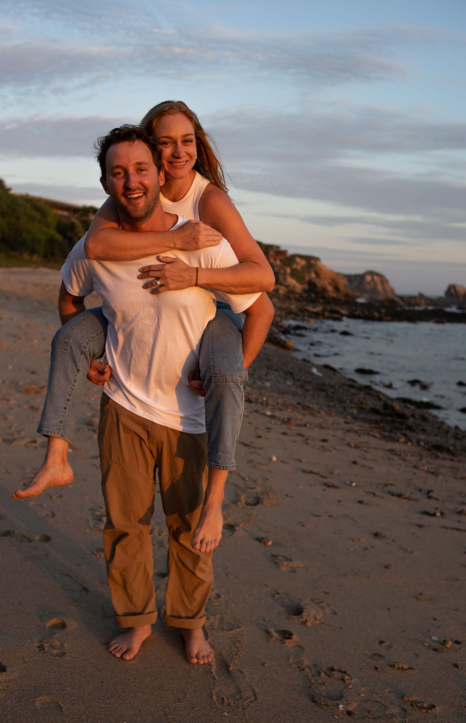 Playful sequence of piggyback rides on a rocky beach at sunset with cliffs in the background.