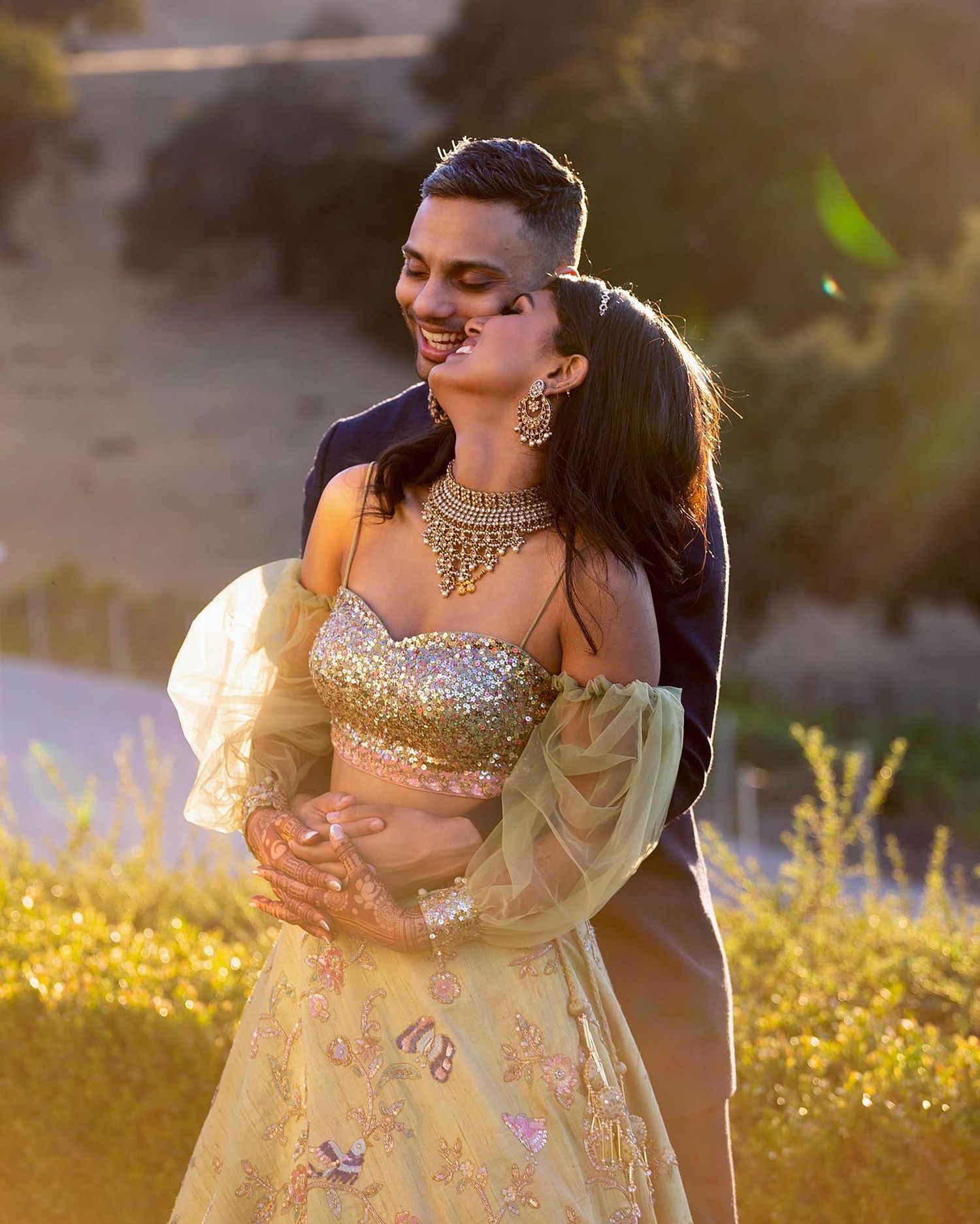 Person wearing ornate gold and cream lehenga in golden sunset light.
