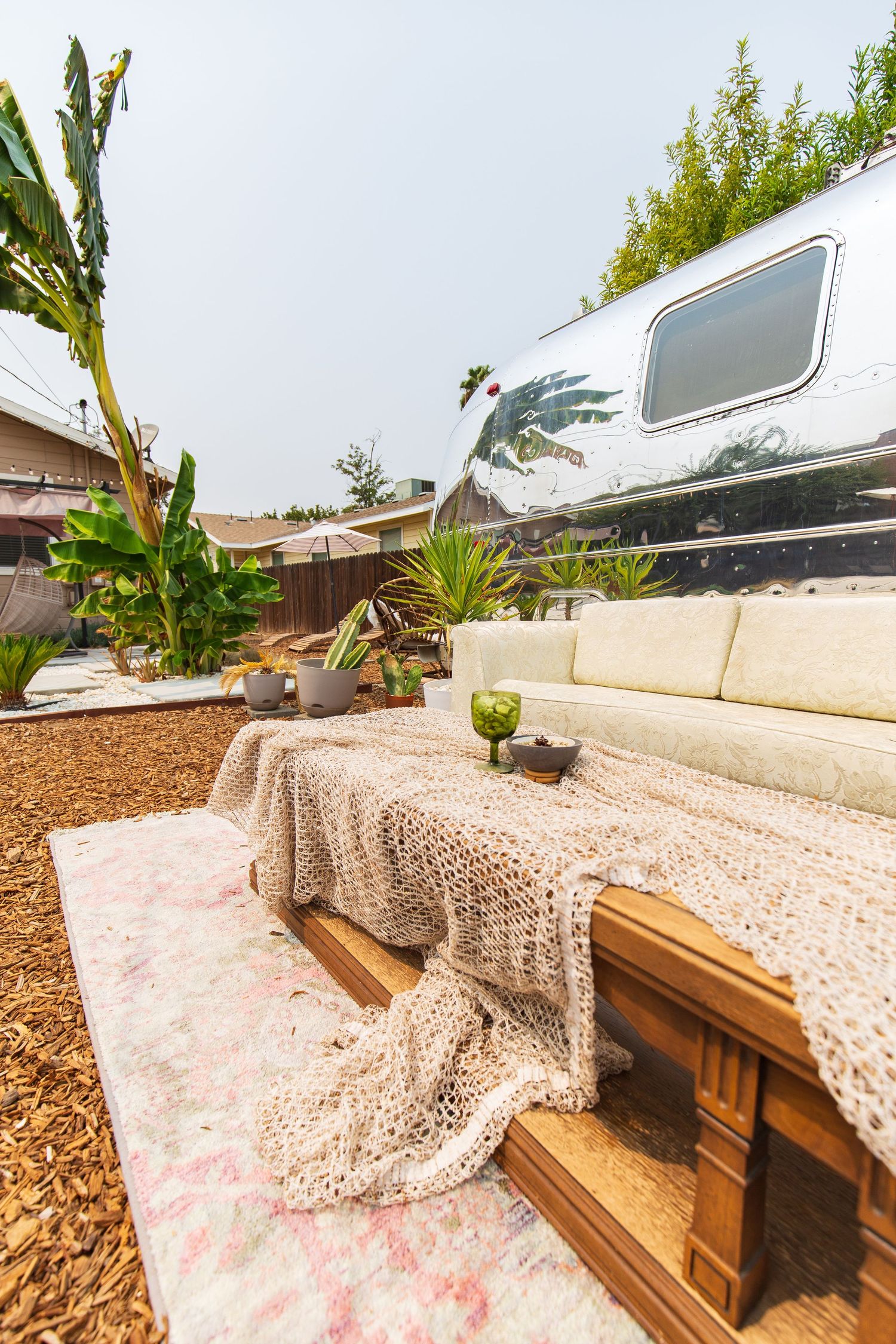 Outdoor seating area with wooden benches covered in pink floral fabric and mulch ground cover in a garden setting.