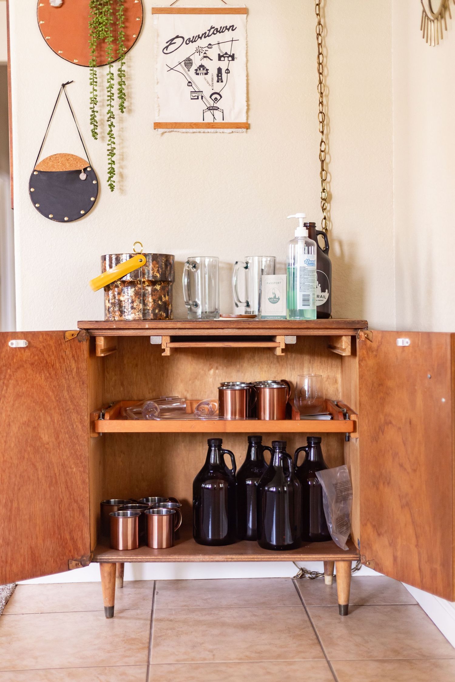 Modern brewery interior with wooden shelving displaying glass growlers and bottles against white walls.