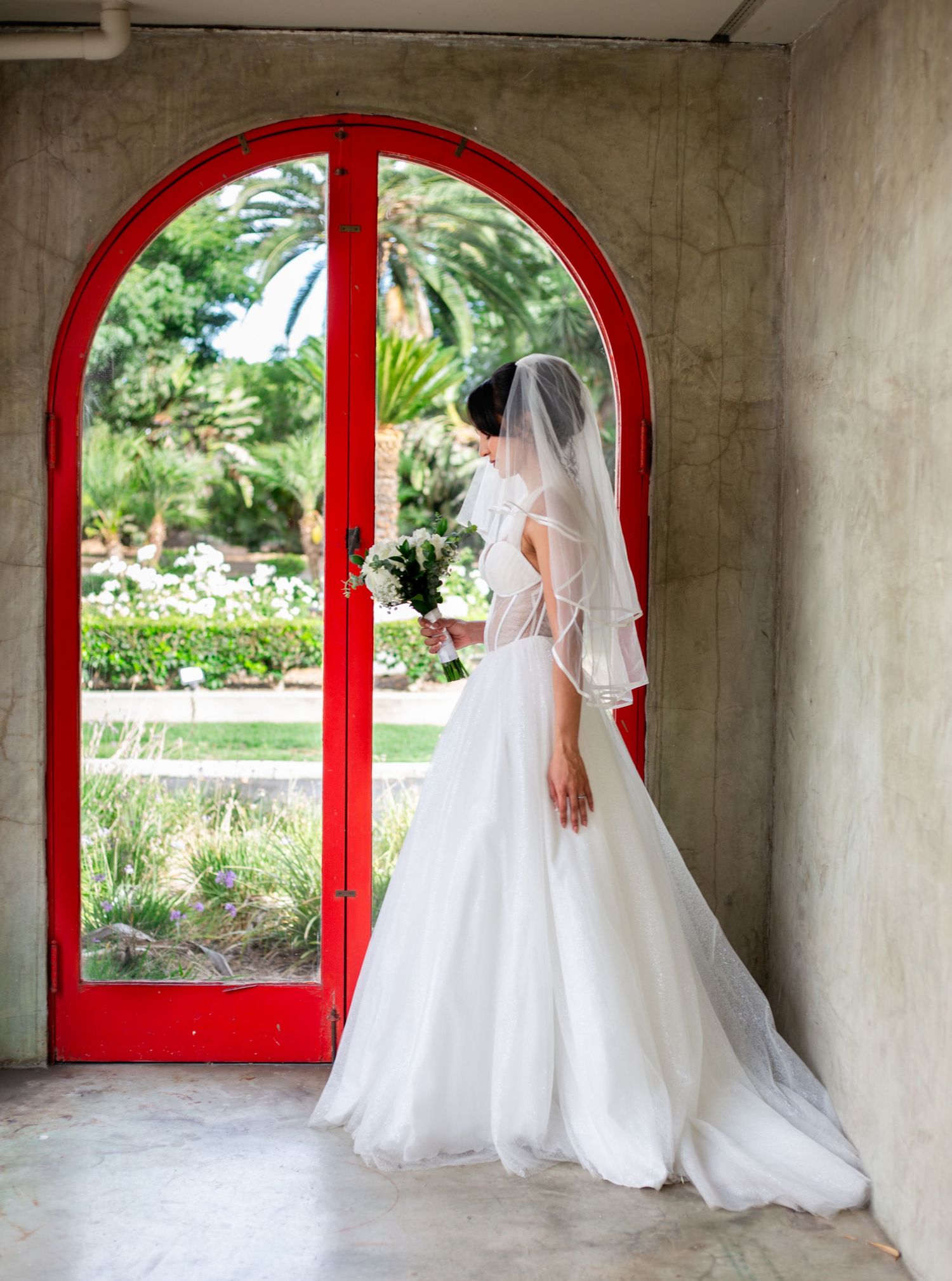 Elegant wedding venue with red arched doors and white columns creates romantic atmosphere.