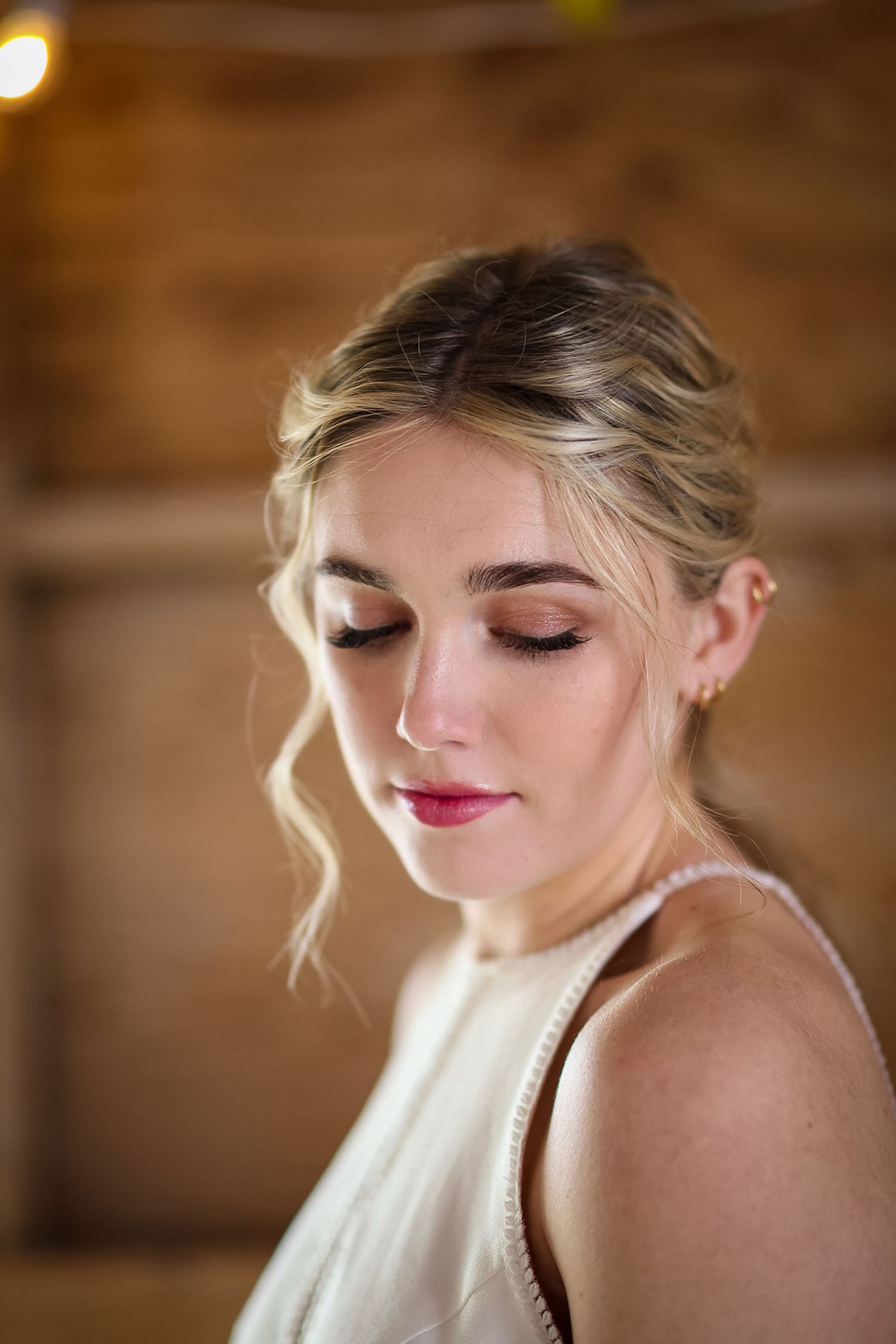 Close-up bridal portrait showing elegant makeup and pearl jewelry against a wooden backdrop.