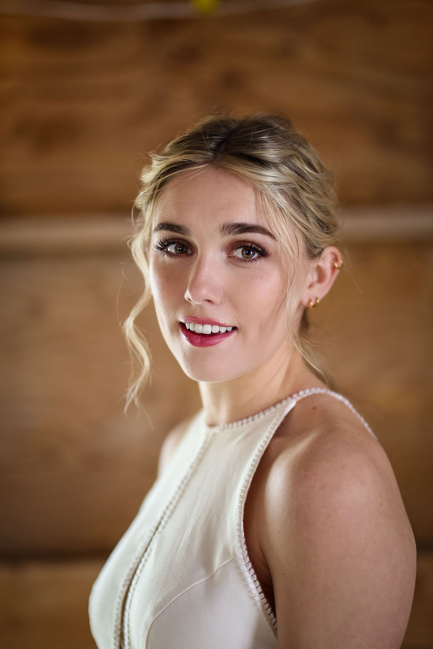 Elegant bridal portrait showing classic makeup and pearl necklace against wooden background.