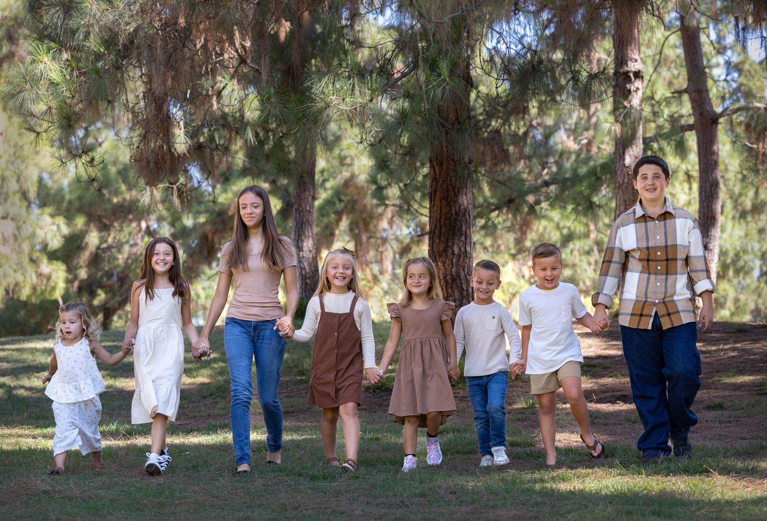 A group of children and adults walking together through a wooded park area.