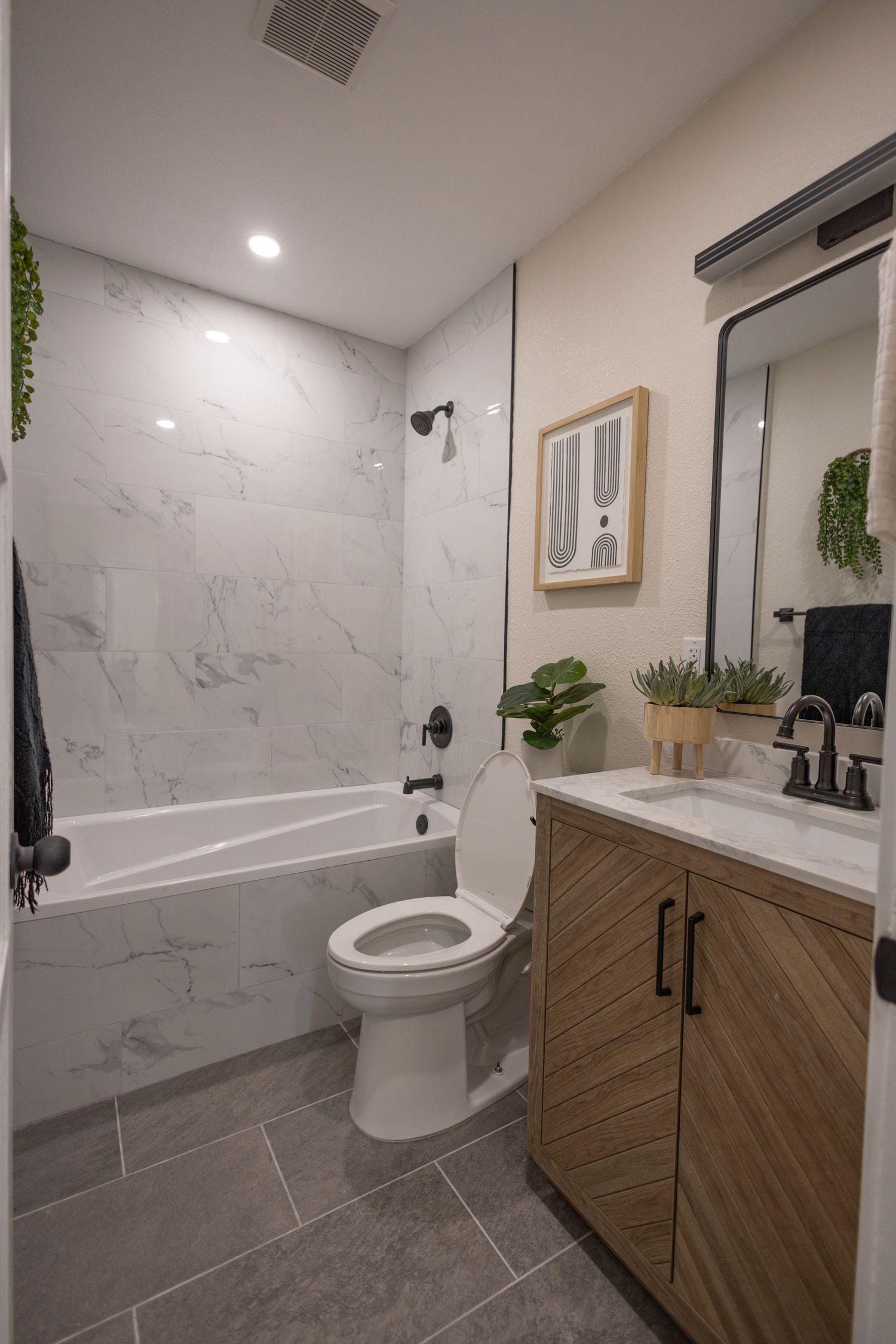 Modern bathroom with marble walls, wooden vanity, grey tile floors and white fixtures showcases clean contemporary design.