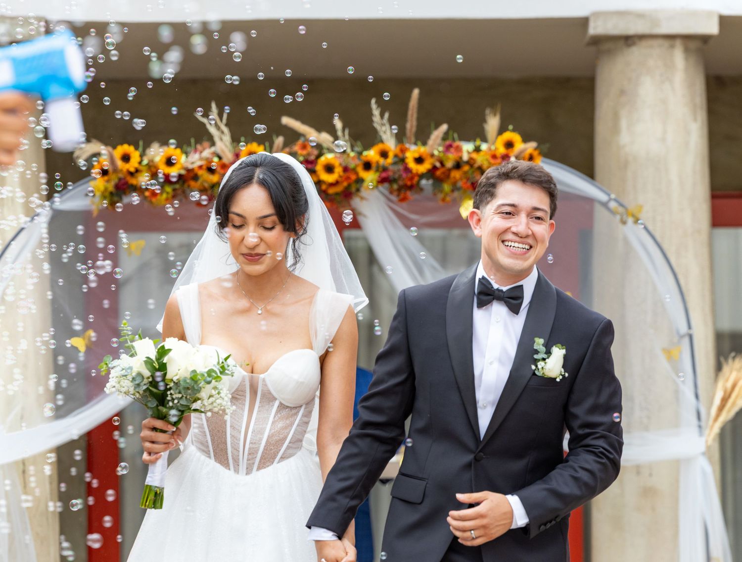 A joyful couple celebrates during their wedding ceremony with confetti and champagne flutes in hand.