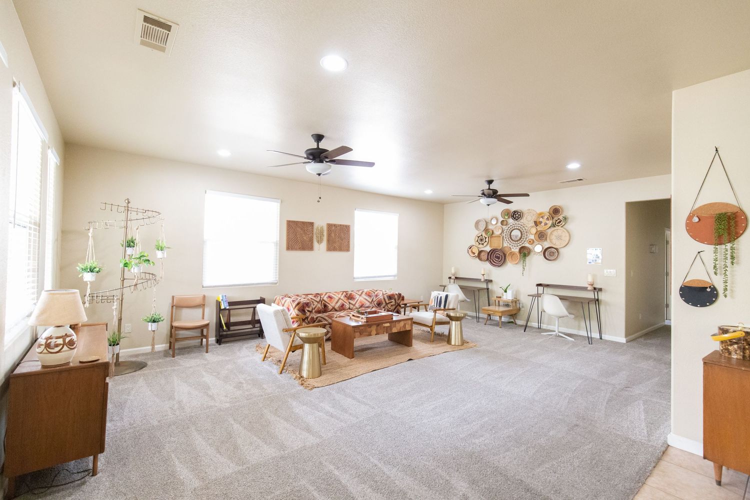 A panoramic view of a modern open-concept living space with white walls, carpet flooring, and recessed lighting.
