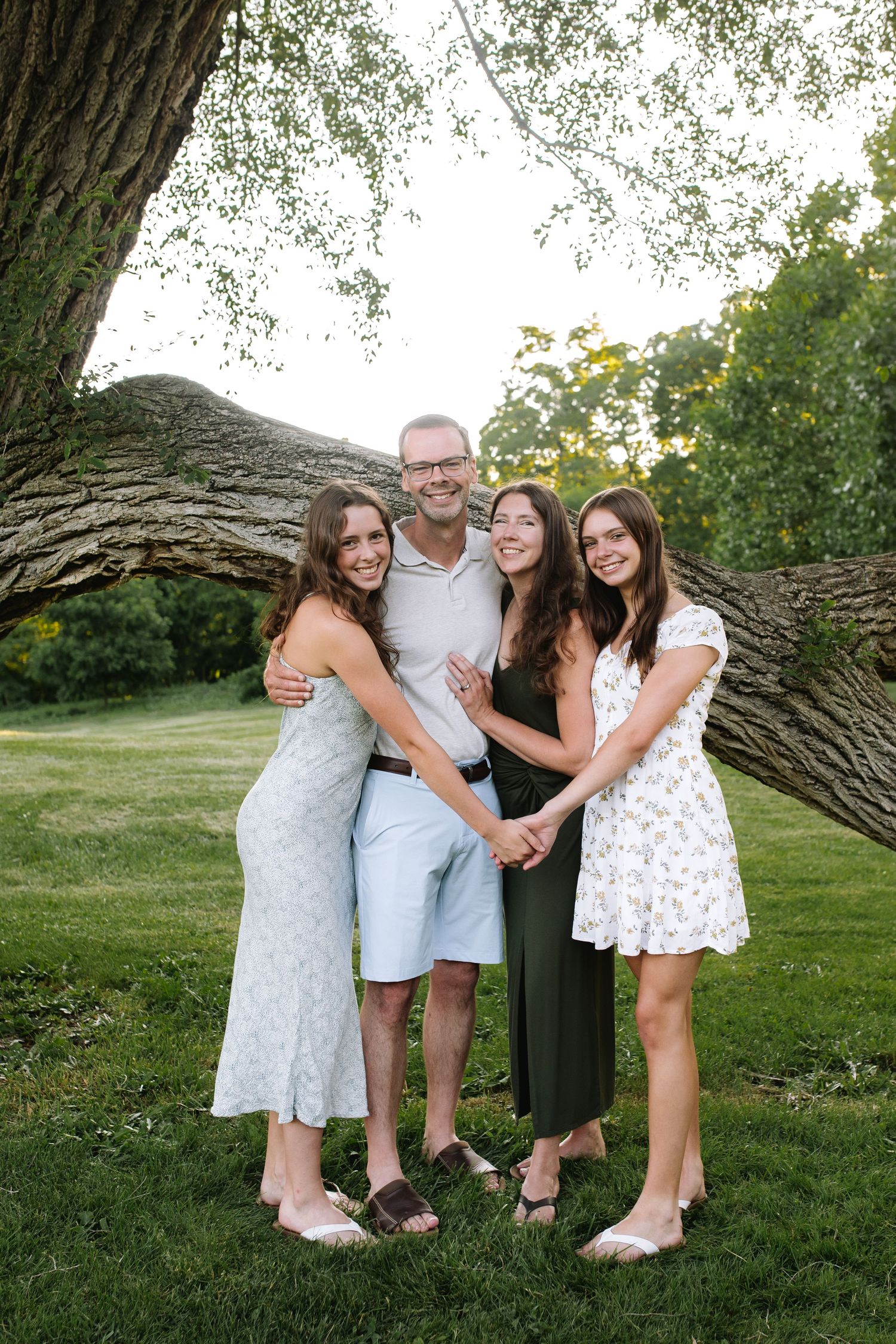Parents and two daughters embrace at the park at bond lake in niagara county during their family session.