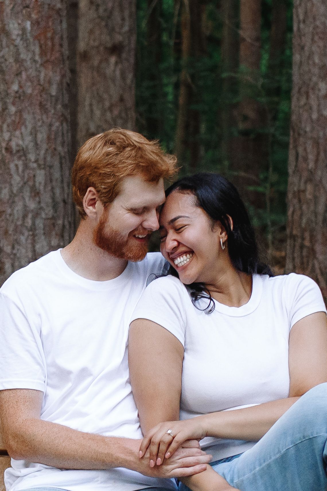 Engaged couple cuddle in the woods at their engagement session at The Eternal Flame in Orchard Park, New York.