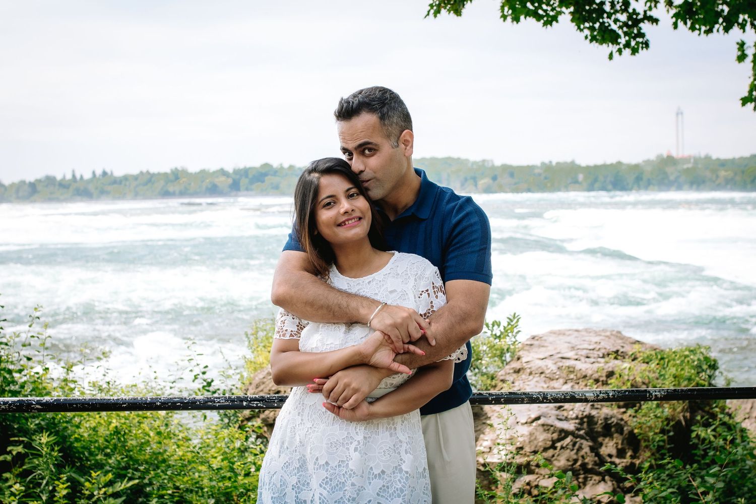 Mom and Dad embrace in front of the rapids in Niagara Falls, New York during their family portrait session.