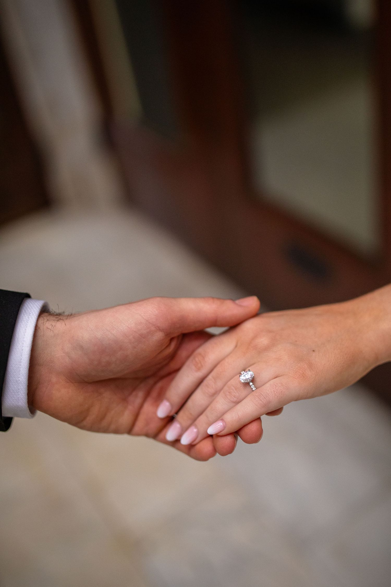 Couple holds hands showcasing the engagement ring at their engagement session at The Ellicott Square Building in Buffalo, New York.