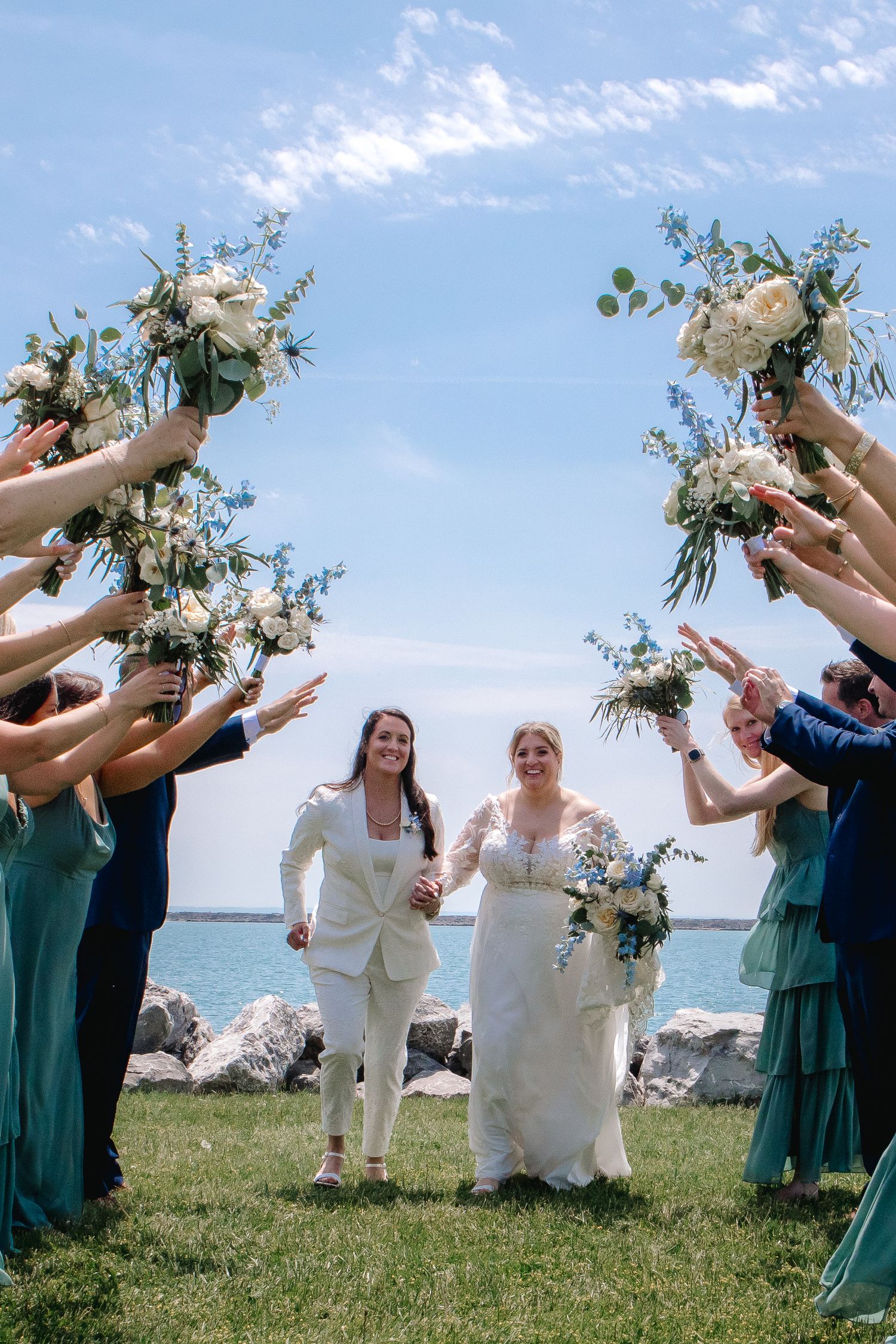 Newly weds and lgbtq couple pose at The Outer Harbor at Wilkeson Pointe in Buffalo, New York after wedding during bridal party portraits.