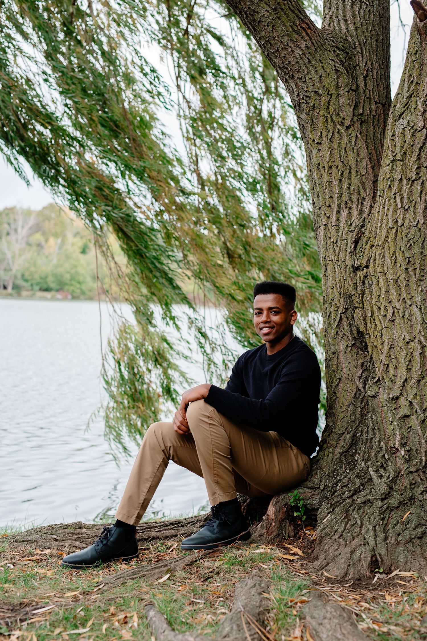 High School Senior Tommy poses under a willow tree during his senior session at hoyt lake in Delaware Park in Buffalo, New York.