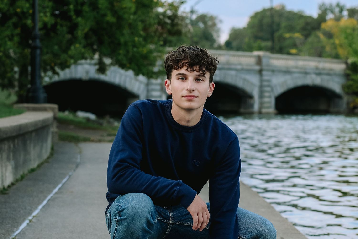 High School Senior Stephen poses by a bridge during his senior session at hoyt lake in Delaware Park in Buffalo, New York.